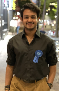 A man wearing a button-up shirt, smiling.